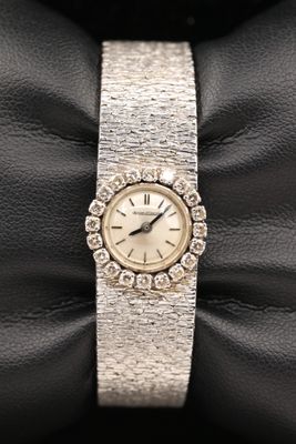 une photo d'une montre pour femme posée sur un sac en cuir noir