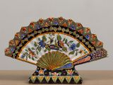 un éventail décoratif posé sur une table, orné de fleurs et d'oiseaux