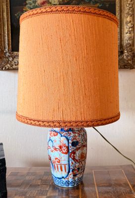 une lampe posée sur une table, avec un tableau accroché au mur en arrière-plan