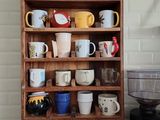 une étagère en bois sur laquelle sont posées de nombreuses tasses à café de différents modèles