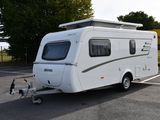 un petit camping-car blanc garé sur un parking