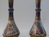 pair of vases with a painting on them sitting on a white surface