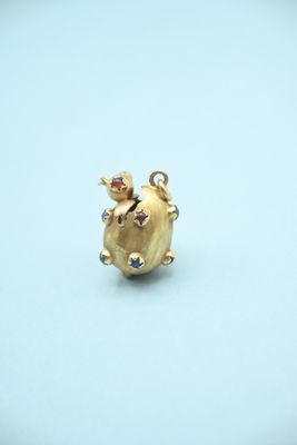 an image of a small gold pig charm with colorful stones on it