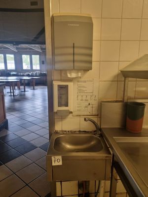 a kitchen with a sink and a counter with a paper towel dispenser on it