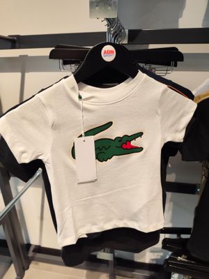 un t-shirt orné d'un crocodile, suspendu à un portant