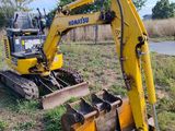 a yellow excavator that is sitting in the grass