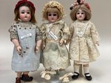 three dolls standing next to each other on a white surface