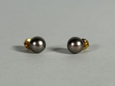 a pair of black pearl earrings on a gray surface