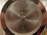 a close up of a silver clock on a table