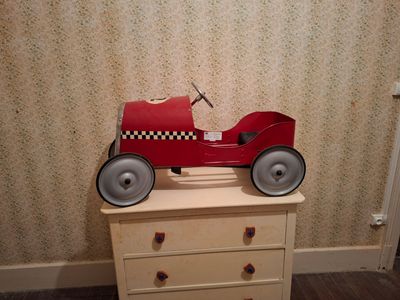 a red toy car sitting on top of a chest of drawers