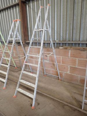 several ladders are lined up against a brick wall in a warehouse