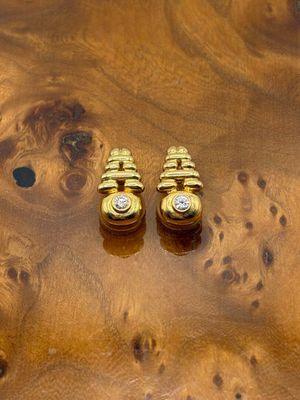 deux paires de boucles d'oreilles en or posées sur une table en bois