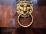 a lion ' s head on the door handle of a chest of drawers