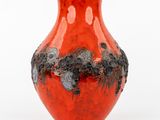a red vase with black flowers on it on a white surface