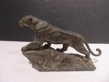bronze statue of a lion on a rock on a white surface