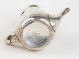 a silver tea pot on a white surface