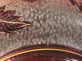 a glass vase that has a red and gold design on it