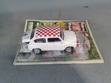 a white toy car with a checkered top on top of a magazine