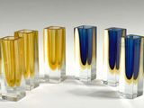 four different colored vases in a row on a white surface