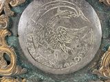 a clock that has a bird on it on it ' s side