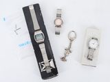 une montre, un porte-clés et un trousseau de clés posés sur une surface blanche