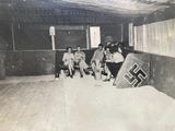 several people sitting in a room with a nazi flag on the wall