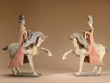 two figurines of a woman riding a horse and a man riding a horse