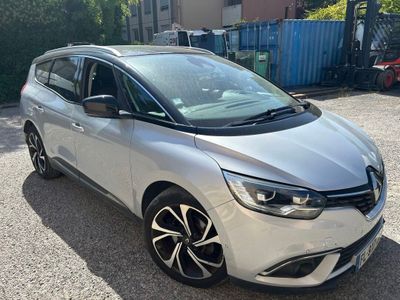 La voiture argentée est garée sur le parking, à côté d'un immeuble.