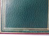 a green leather book with a gold border on it