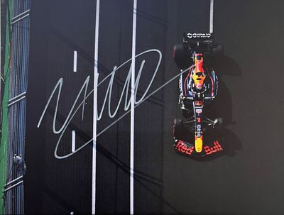 Une voiture de course Red Bull sur la piste, devant un grand écran