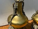 deux vases en or posés sur une table, avec un mur blanc en arrière-plan