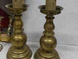 pair of antique brass candlesticks on a table with a mirror in the background