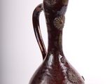 a brown vase that is sitting on a white surface