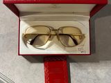 des lunettes dans une boîte rouge posée sur une table, à côté d'un livre rouge