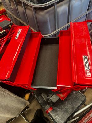 une boîte à outils rouge posée sur une pile d'outils