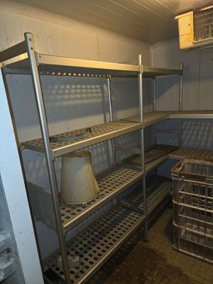 a metal shelf with baskets on it in the corner of a room