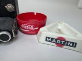 a coke can, a cigarette holder, and a cigarette ashtray on a table