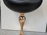 a black bowl sitting on top of a gold pedestal