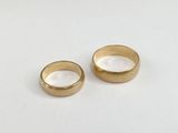 two gold wedding rings on a white surface