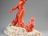 an orange sculpture of a woman and a dog on a rock