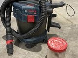 un aspirateur posé par terre à côté d'un bac de collecte