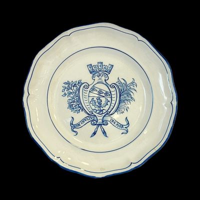 une assiette bleue et blanche sur laquelle figure un blason