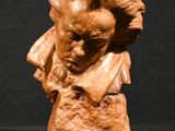 sculpture représentant le buste d'un homme coiffé d'un chapeau, sur fond noir