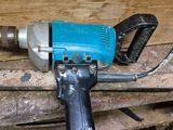 une perceuse bleue posée sur un morceau de bois