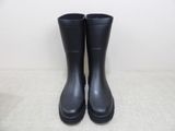 black rain boots on a white surface with a white wall in the background