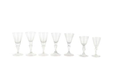 six verres à vin transparents alignés sur une surface blanche
