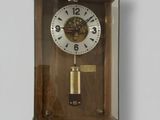 une horloge en bois avec une vitre, accrochée au mur