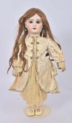 un gros plan d'une poupée aux longs cheveux vêtue d'une robe dorée