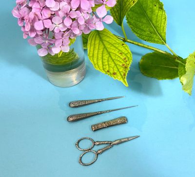 three pairs of scissors sitting next to a vase of flowers