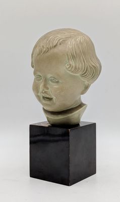 a close up of a sculpture of a child ' s head on a black stand